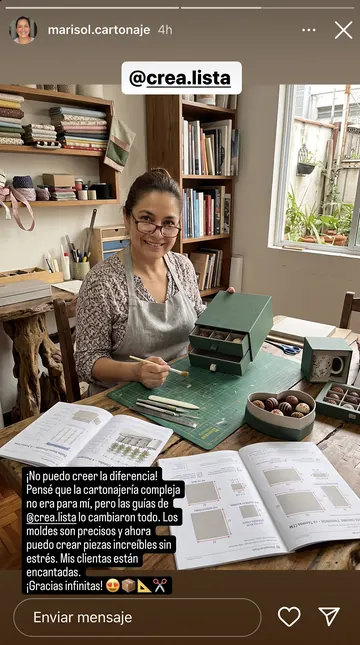 Artesana con las láminas impresas en la mesa, junto a las cajas producidas