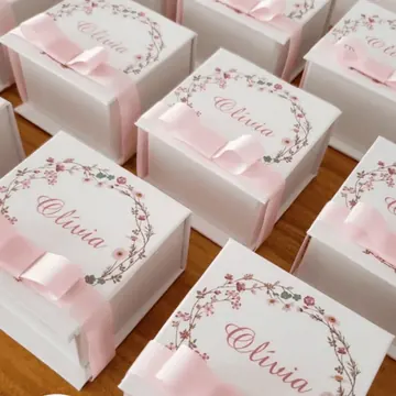 Recuerdos blancos con guirnalda floral, nombre personalizado y lazo de satén rosa
