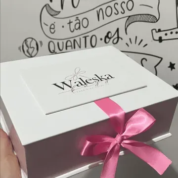 Caja blanca personalizada con lazo fucsia, sostenida en la mano